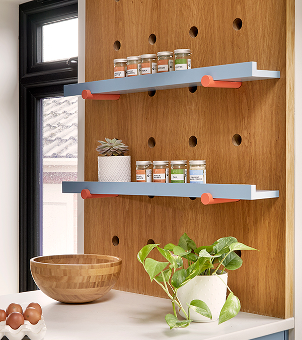 Detail of the bespoke wooden panel created to accommodate the cooking seasoning  jars with nice blue adjustable shelves and statement terracotta adjustable supports.