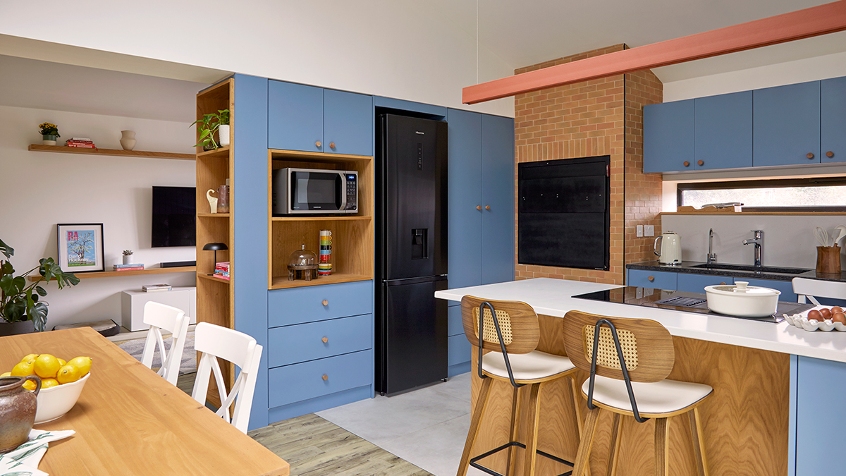 View of the Kitchen/Dinning space visually integrated with the TV Room where the bespoke bue and wooden modern joinery dividing the two spaces accommodate all appliances.