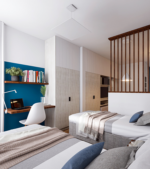 A bedroom filled with natural light, featuring a sleek, modern built-in wardrobe and a desk area set off by a blue-painted wall. The space is seamlessly integrated with the living area through a see-through partition, maintaining an open and airy feel.